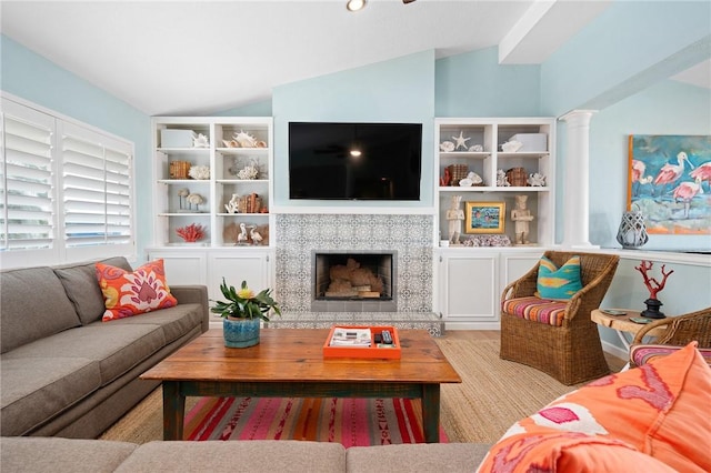 living room with ornate columns, vaulted ceiling, and a tile fireplace