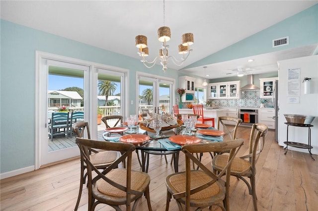 dining space featuring visible vents, vaulted ceiling, french doors, light wood-type flooring, and a chandelier