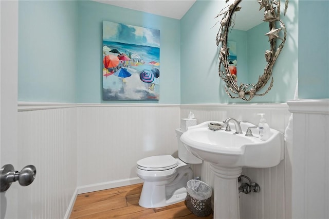 half bath featuring toilet, a wainscoted wall, and wood finished floors