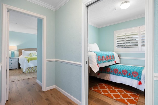 bedroom featuring ornamental molding, hardwood / wood-style floors, and baseboards