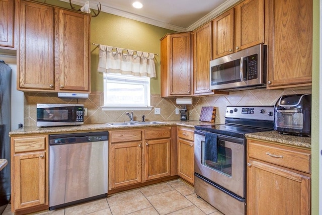 7009 Tocken Ct, Corpus Christi, TX 78414 - kitchen featuring appliances with stainless steel finishes, ornamental molding, tasteful backsplash, light tile patterned flooring, and brown cabinets
