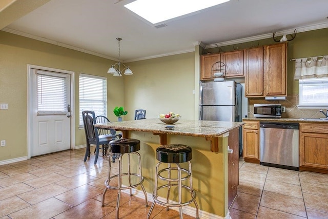 7009 Tocken Ct, Corpus Christi, TX 78414 - kitchen with stainless steel appliances, a kitchen island, brown cabinetry, backsplash, and crown molding