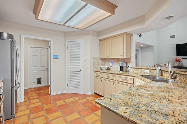 107 Angelfish, Aransas Pass, TX 78336 - kitchen with freestanding refrigerator, cream cabinets, tasteful backsplash, and light stone counters