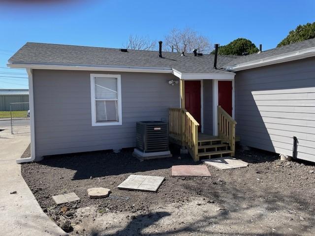 back of house featuring a shingled roof and central AC unit