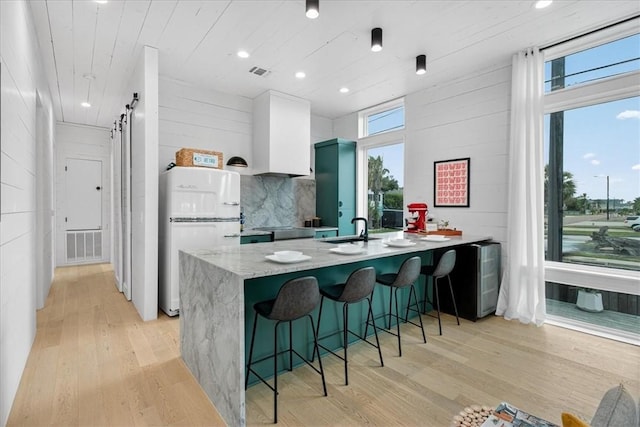 602 Island Retreat Ct, Port Aransas, TX 78373 - kitchen with white refrigerator, light wood-style floors, white cabinetry, a kitchen bar, and recessed lighting
