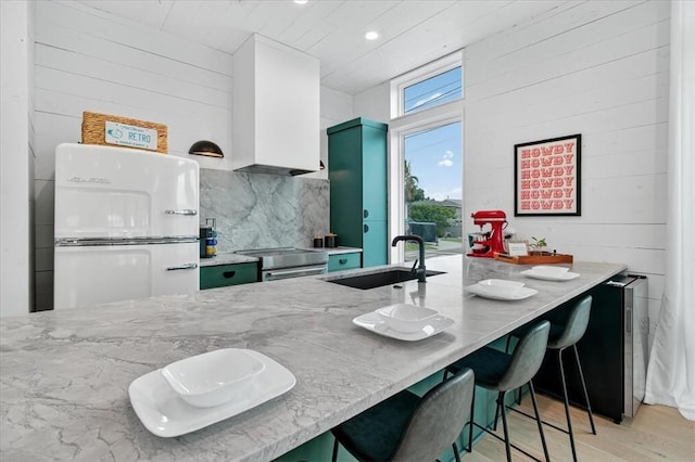 602 Island Retreat Ct, Port Aransas, TX 78373 - kitchen featuring stainless steel range with electric cooktop, light wood-style floors, light stone counters, decorative backsplash, and a kitchen bar