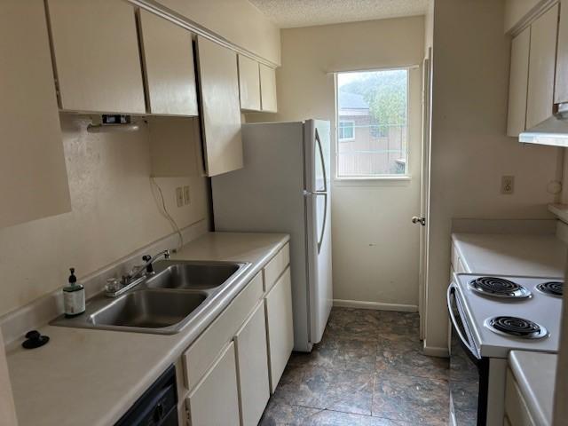 kitchen featuring white appliances, sink, a textured ceiling, and white cabinets