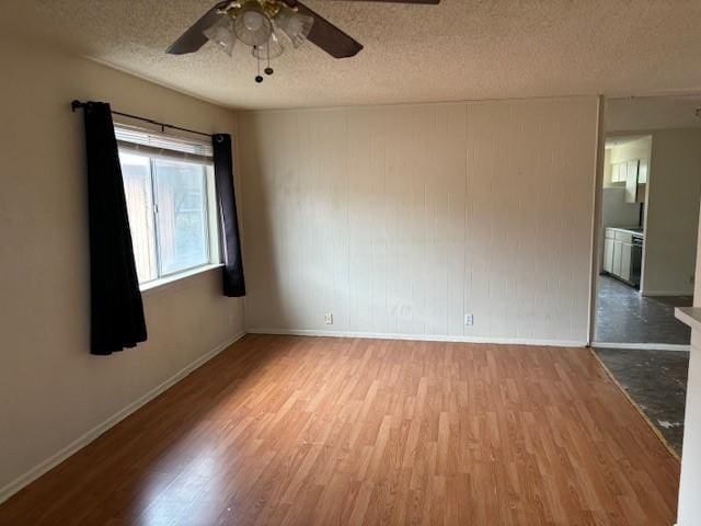 empty room featuring ceiling fan, hardwood / wood-style floors, and a textured ceiling