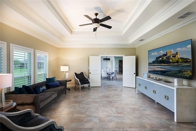 living room with crown molding, a tray ceiling, and ceiling fan