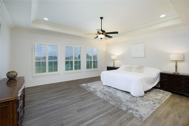 bedroom featuring crown molding, hardwood / wood-style floors, a tray ceiling, and ceiling fan