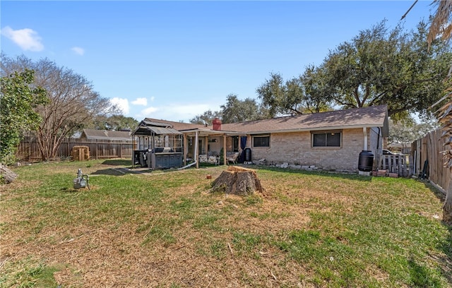 rear view of property with brick siding, a lawn, and a fenced backyard