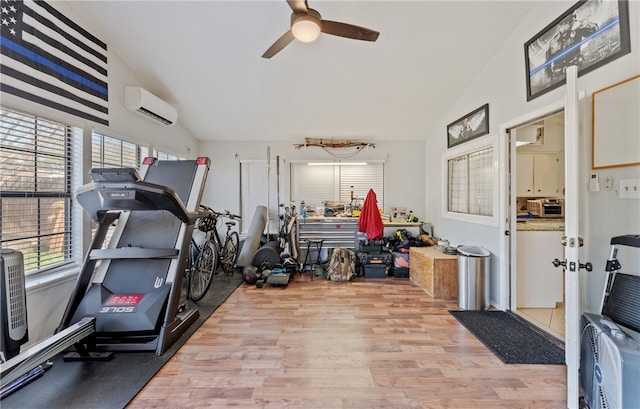 workout room featuring vaulted ceiling, an AC wall unit, plenty of natural light, and light wood-style flooring