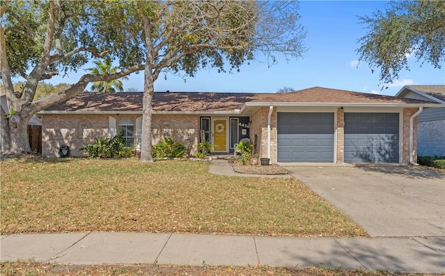 single story home featuring an attached garage, driveway, a front lawn, and brick siding