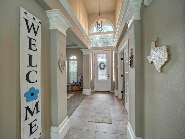 foyer with baseboards, a notable chandelier, a textured wall, and light tile patterned floors