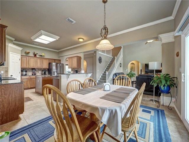 dining space featuring visible vents, crown molding, stairs, arched walkways, and light tile patterned floors