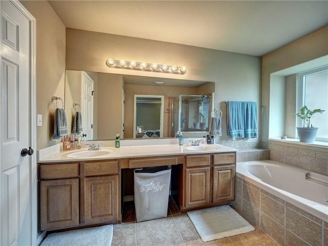 full bathroom with double vanity, a shower stall, a sink, and a garden tub