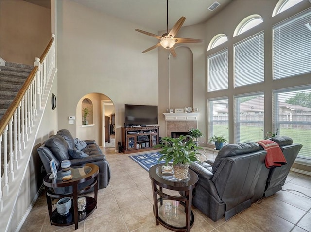 living room with ceiling fan, arched walkways, plenty of natural light, a towering ceiling, and visible vents