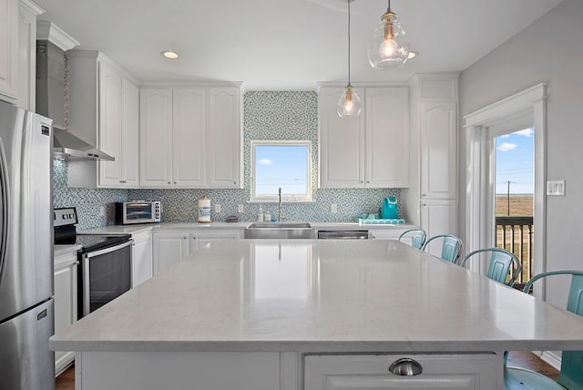 kitchen featuring a healthy amount of sunlight, a kitchen island, stainless steel appliances, and a sink