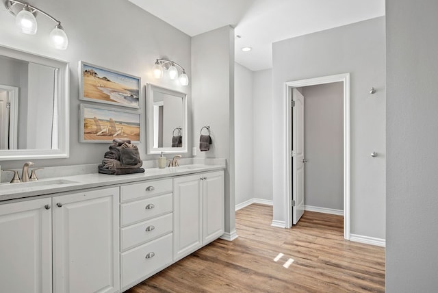 bathroom with double vanity, a sink, baseboards, and wood finished floors