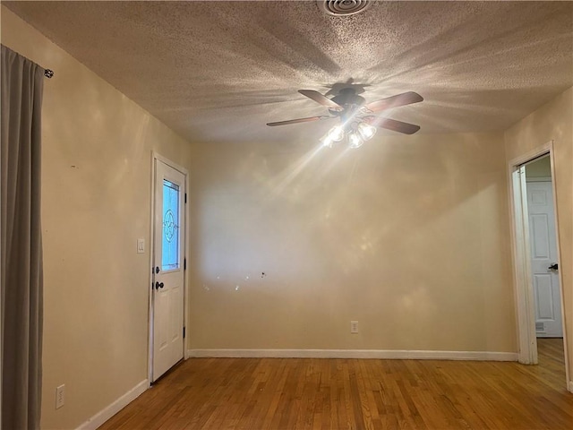 spare room with a ceiling fan, baseboards, light wood finished floors, and a textured ceiling