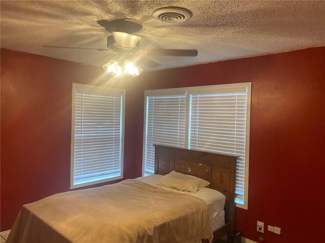 bedroom with visible vents, a ceiling fan, and a textured ceiling