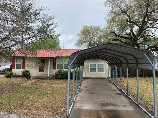 view of front of home with a front yard, fence, a detached carport, and metal roof
