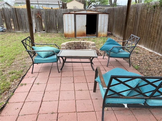 view of patio / terrace with an outbuilding, an outdoor fire pit, a fenced backyard, and a storage shed