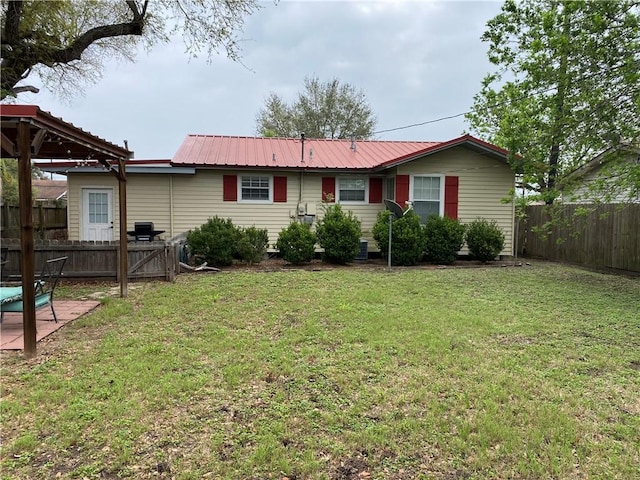 view of front facade with a patio, a front yard, fence, and metal roof