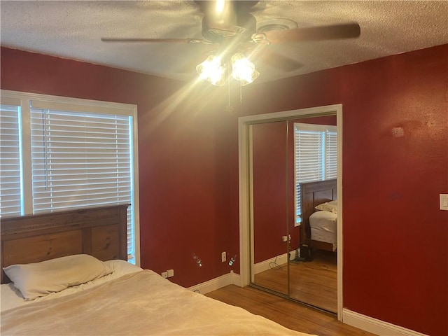 bedroom featuring a ceiling fan, a textured ceiling, baseboards, and wood finished floors
