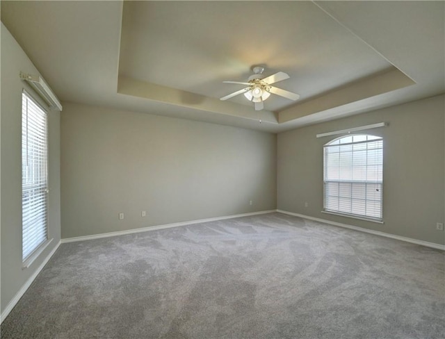 carpeted spare room featuring ceiling fan and a tray ceiling