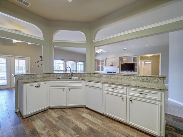 kitchen with white cabinetry, sink, a kitchen island with sink, white dishwasher, and light hardwood / wood-style flooring