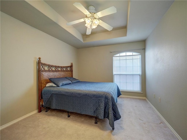 carpeted bedroom featuring ceiling fan and a raised ceiling