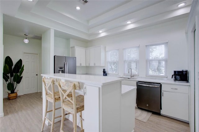 kitchen with a raised ceiling, sink, appliances with stainless steel finishes, a kitchen island, and white cabinetry