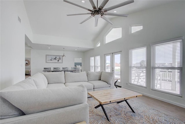 living room with light wood-type flooring, high vaulted ceiling, and ceiling fan