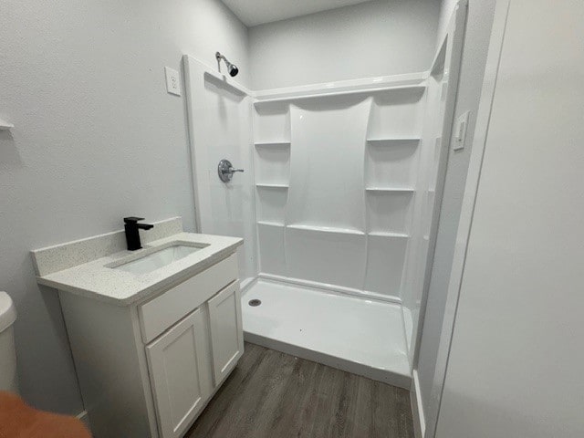 bathroom with toilet, a shower, vanity, and hardwood / wood-style flooring