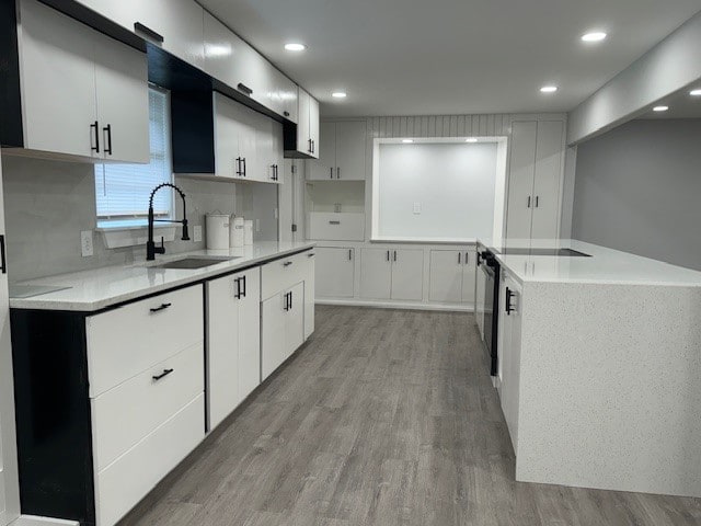 kitchen featuring white cabinetry, sink, light wood-type flooring, and decorative backsplash