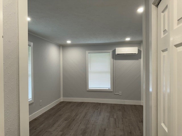 unfurnished room featuring a wall mounted AC, dark hardwood / wood-style floors, and crown molding