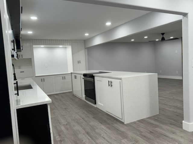 kitchen featuring white cabinetry, light hardwood / wood-style floors, sink, and electric stove