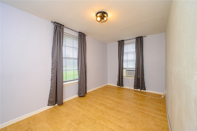 empty room featuring light wood-type flooring, cooling unit, and baseboards