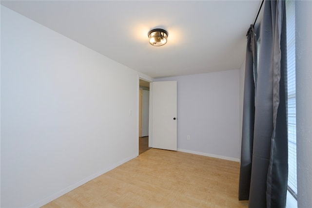 spare room featuring baseboards and light wood-style floors