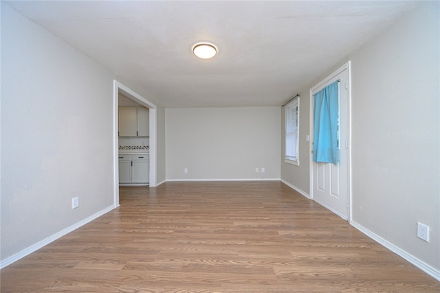 spare room with baseboards and light wood-style floors