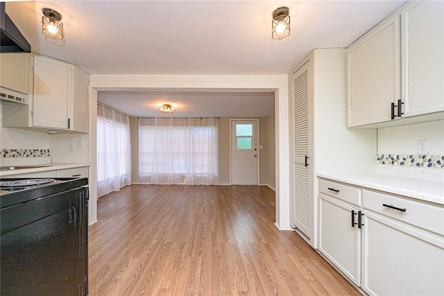 kitchen featuring white cabinets, black range with electric cooktop, and light wood-type flooring