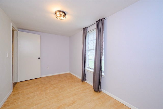 unfurnished room with light wood-type flooring and baseboards