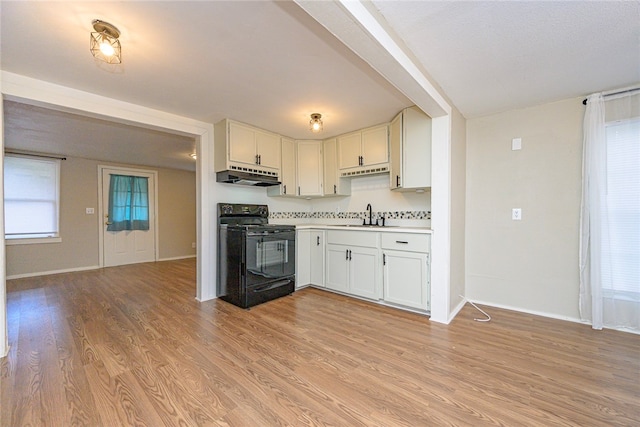 kitchen with sink, light wood-type flooring, black / electric stove, and white cabinets