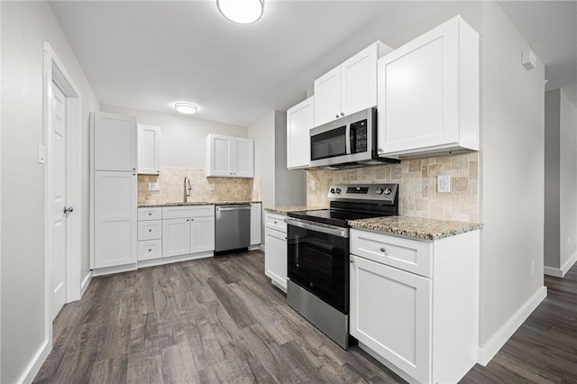 936 S 10th St, Aransas Pass, TX 78336 - kitchen with a sink, stainless steel appliances, white cabinets, dark wood-type flooring, and tasteful backsplash