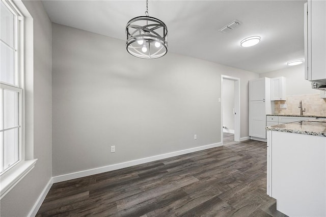 936 S 10th St, Aransas Pass, TX 78336 - unfurnished dining area featuring an inviting chandelier, visible vents, baseboards, and dark wood-style floors