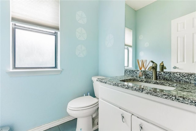 half bathroom with vanity, toilet, and baseboards