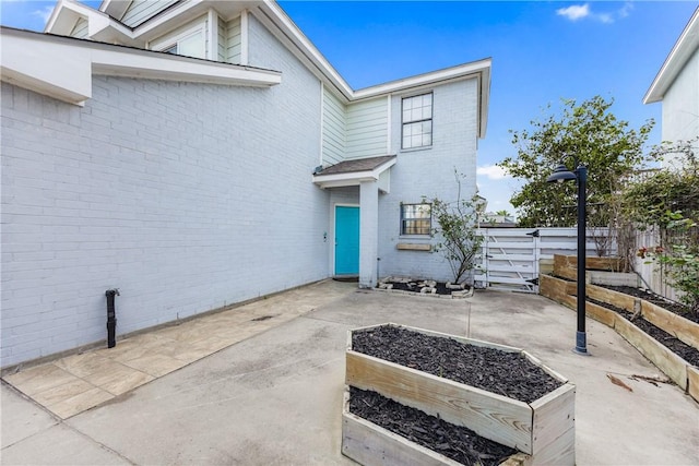 property entrance featuring a patio area, brick siding, and fence