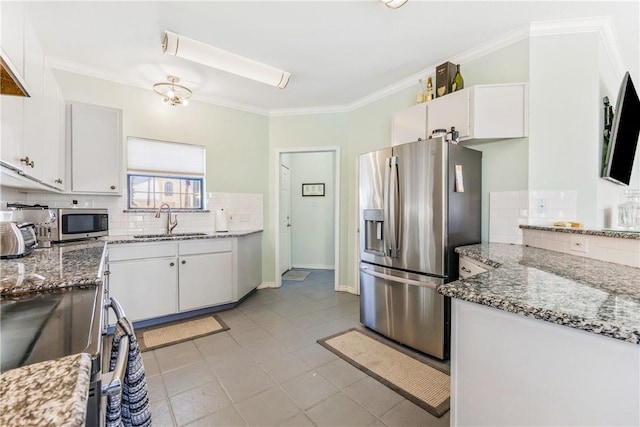 kitchen with white cabinets, appliances with stainless steel finishes, a sink, crown molding, and backsplash