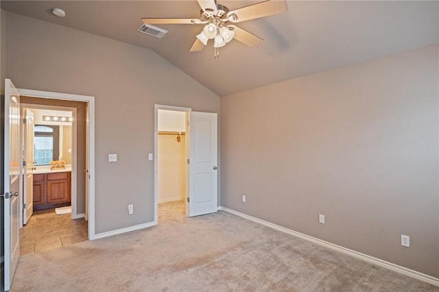 unfurnished bedroom featuring a spacious closet, lofted ceiling, ceiling fan, a closet, and light colored carpet